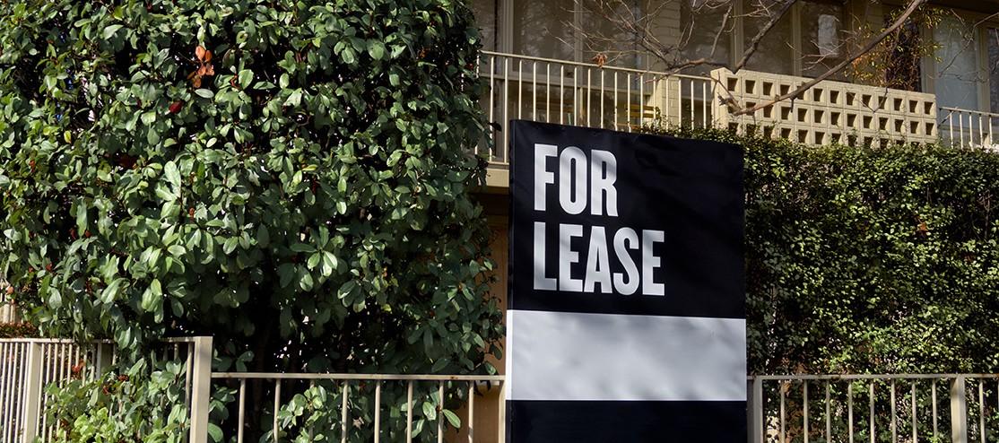 Apartment building with 'for lease' sign at front in daylight